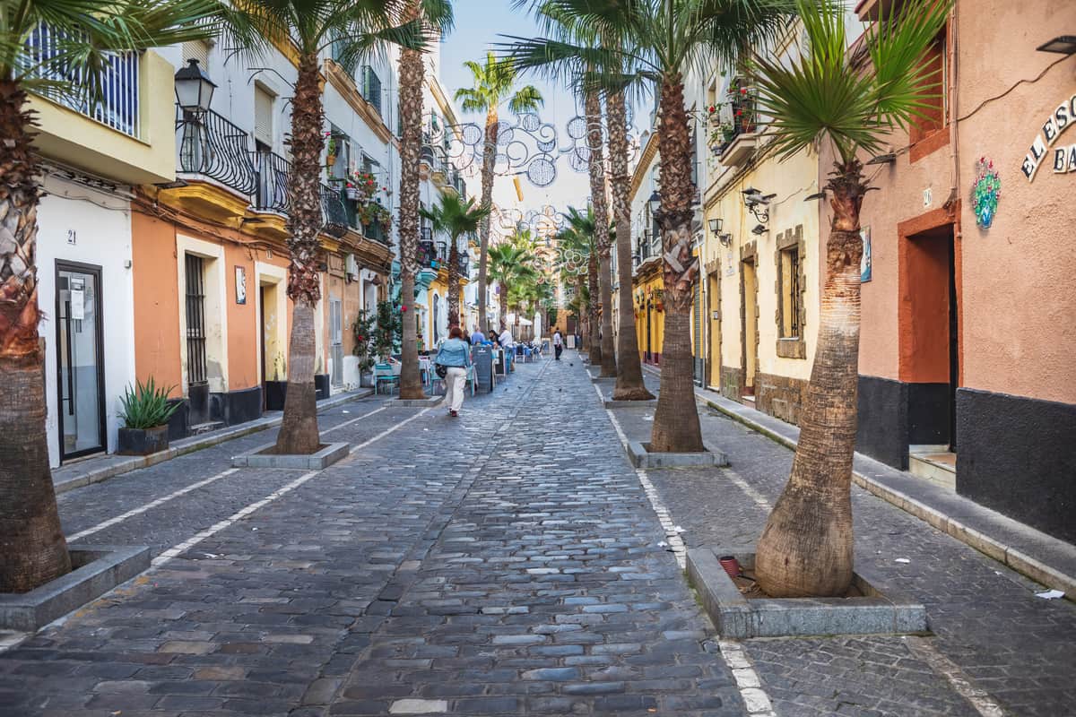 a street with colorful houses and palm trees; Cadiz, Spain