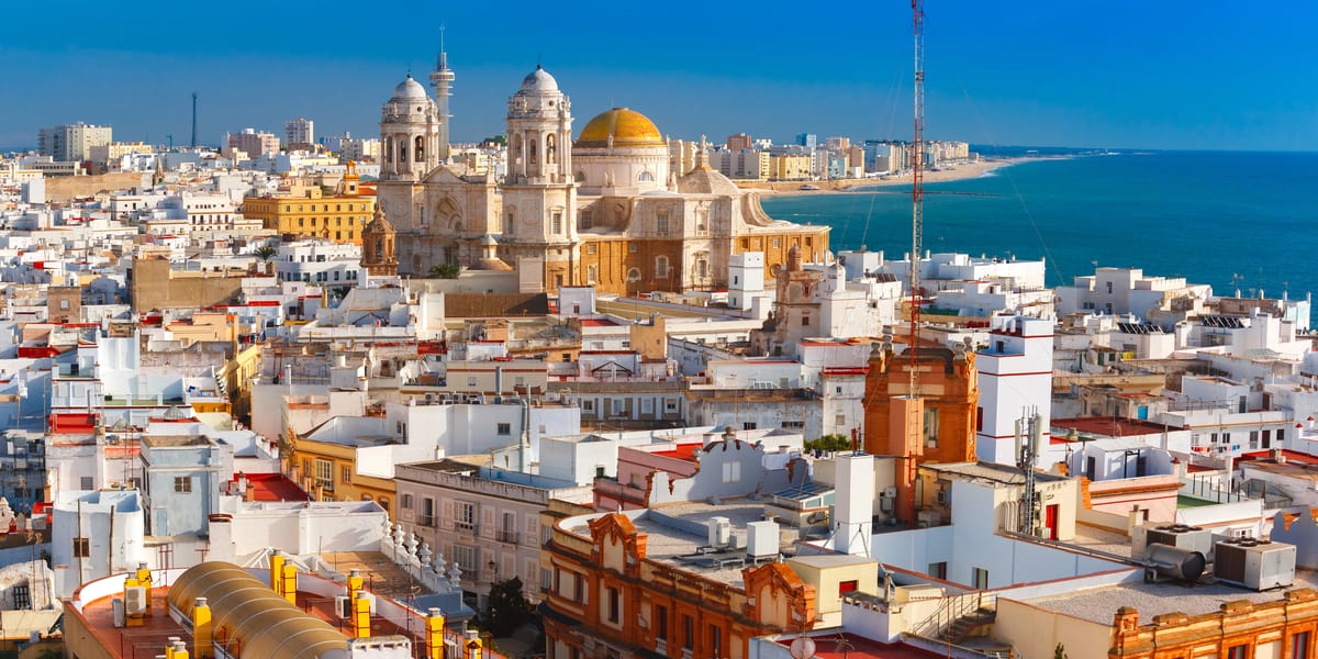 a view of of Spanish city with white houses and a cathedral in the middle, the sea the right side; Cadiz City in Andalusia, Spain