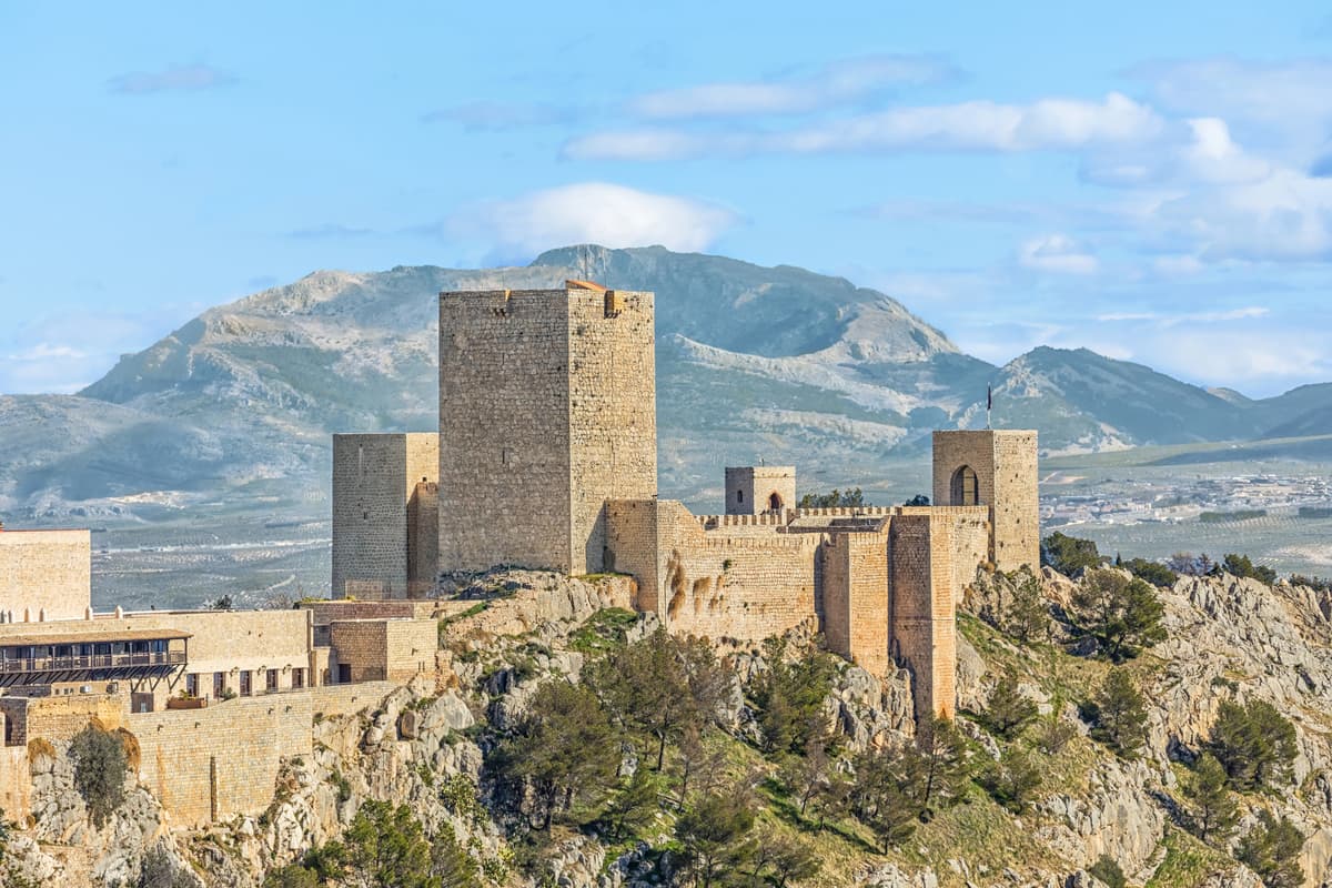 a medieval fortress with towers and bulwarks and mountains at the background; Castle of Santa Catalina in Jaen