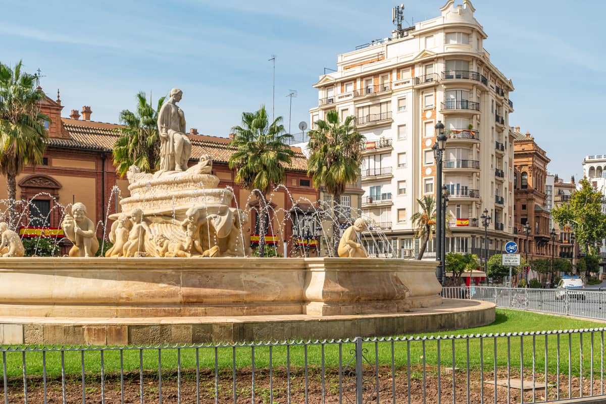 a square with a large fountain with lots of figures; Fuente de Hispalis in Seville, Spain