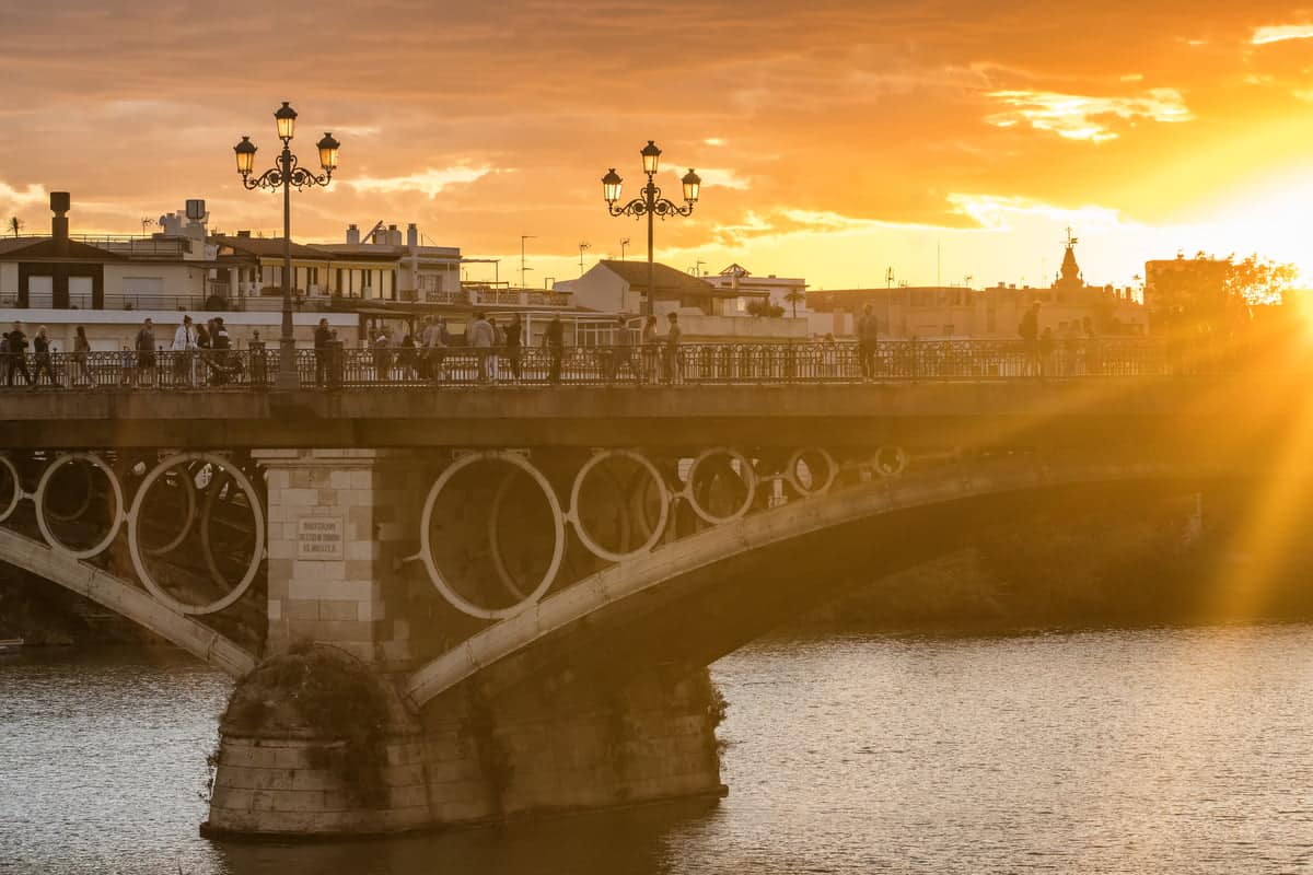 a bridge above a river at sunset; Puente de Triana in Seville, Andalusia