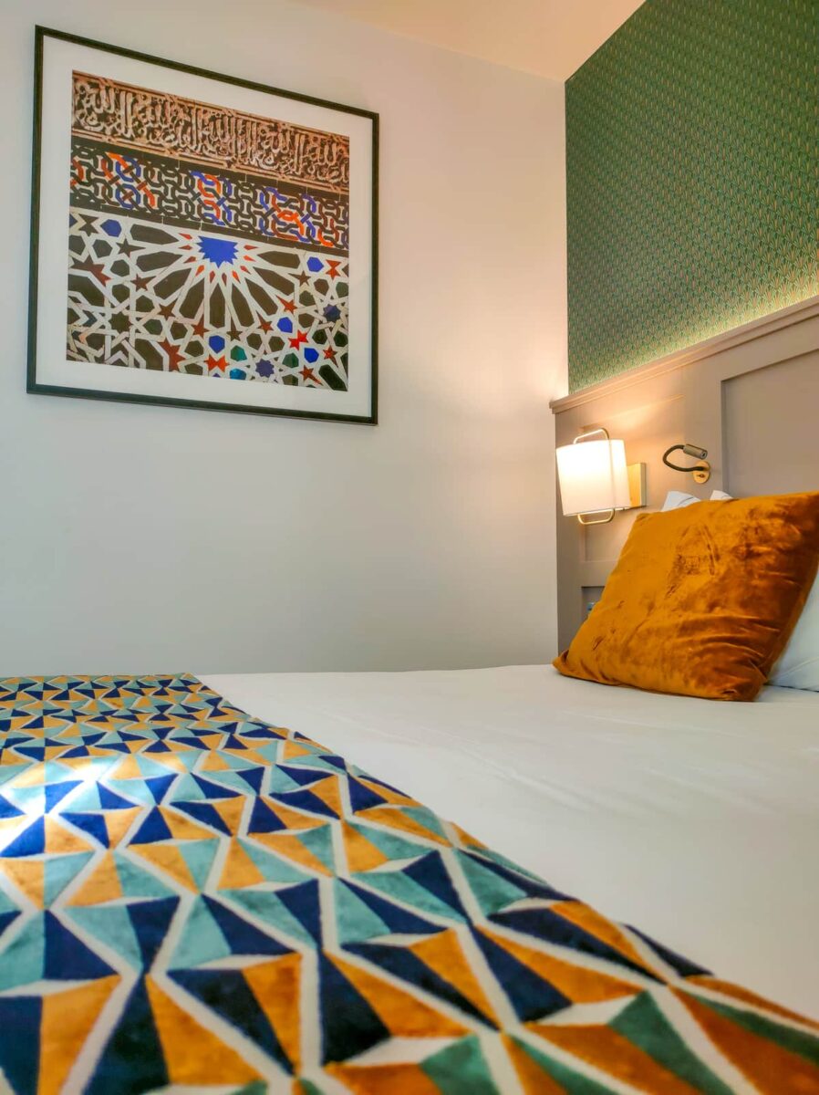 a bed in a hotel room with a photograph of mosaic from Alhambra, a room in the Eurostars Puerta Real Hotel in Granada, Spain