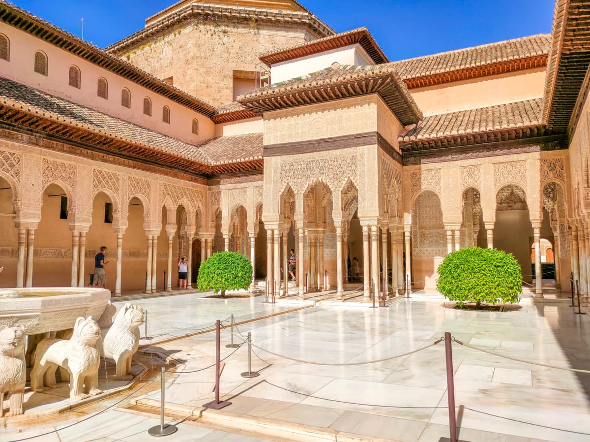 a Moorish type of architectures with columns and arches surrounding a patio with a fountain with lions, the Patio of the Lions in the Alhambra, Granada, Spain